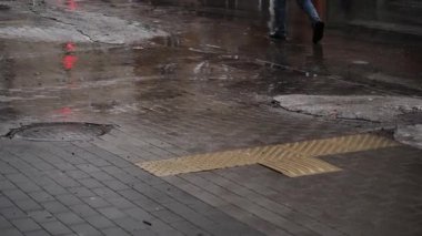 Yayaların ve arabaların kaldırım taşlarının üzerindeki su birikintisinde yansıması. Baharda eriyen kar ve yağmur birikintisi.
