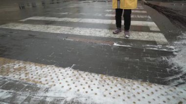 Kaldırımı süpüren bir kamu görevlisinin elindeki süpürgeye yakın çekim. Turuncu yelekli bir hademe yaya yolunda kar temizliyor..