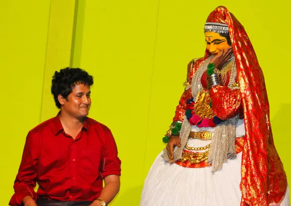 MUNNAR, INDIA - 10 Şubat 2016: Kathakali dansçısı, Hindistan 'ın Kerala eyaletinde Munnar' da kadın izleyiciyle birlikte sahne alıyor. Punarjani Geleneksel Köy Munnar. Kırmızı gömlekli izleyici