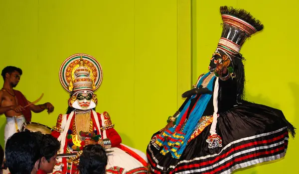 MUNNAR, INDIA - 10 Şubat 2016: Kathakali dansçısı, Hindistan 'ın Kerala eyaletinde Munnar' da diğer iki sanatçıyla performans sergiledi ve seyirci performanslarını izledi.