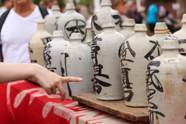 Bit pazarındaki bir kadının eli geleneksel Japon vazolarını işaret ediyor.