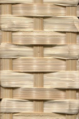 Karmaşık bir şekilde örülmüş hasır hasırın yakın çekimi ayrıntılı işçiliği ve doğal maddeleri yumuşak, nötr tonlarda sergiliyor.