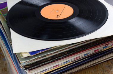 Renkli albüm kapakları, klasik müzik, retro ses ve nostaljiyi sembolize eden istiflenmiş vinil plaklar koleksiyonu..