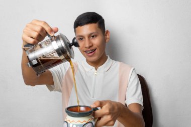 Genç Meksikalı adam zanaatkar bardağında kahve servisi yapıyor.