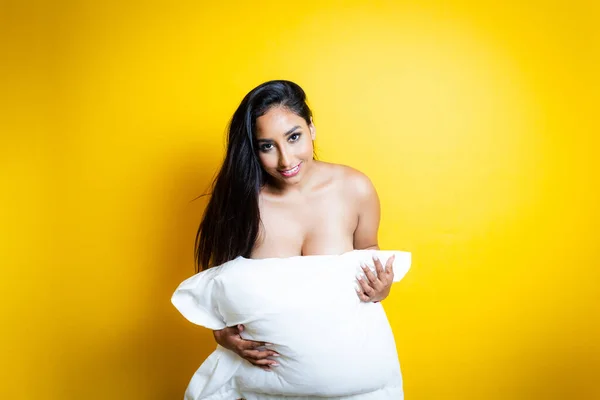 官能的な裸のヒスパニック系女性カバー彼女の体とともに枕 ロイヤリティフリーのストック写真