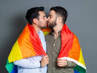 Igbt gurur bayrağıyla sarılıp öpüşen eşcinsel çiftin portresi.