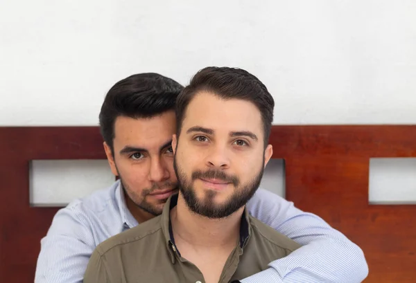 ゲイのカップルがベッドに座ってカメラを見ている姿を ロイヤリティフリーのストック画像