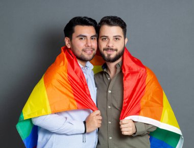 gay couple of diverse men embracing with lgbt rainbow flag
