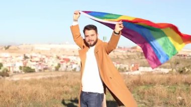 young caucasian homosexual man holding lgbt flag outdoors on gay pride day