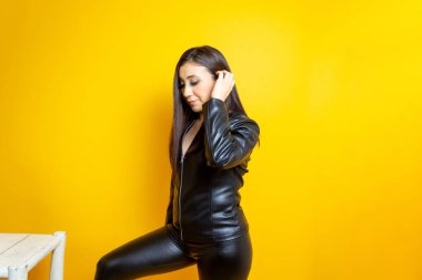 beautiful middle aged woman in leather clothes putting foot up on chair