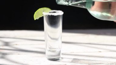 close up slow motion of bottle serving shot of tequila, mezcal