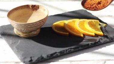 slow motion of person pouring ground chile and salt of worm on orange slices next to shot of mezcal. tequila
