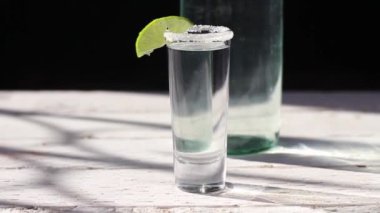 slow motion slider of frosted silver tequila shot with lemon slice