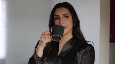 Güzel ve genç İspanyol iş kadını kendinden emin ve mutlu bir tavırla kahve içiyor.