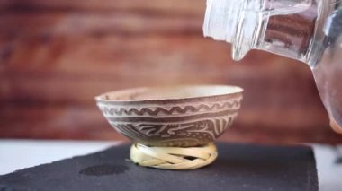 Geleneksel bardağa mezcal ya da gümüş tekila dökerken yakın çekim, jicara
