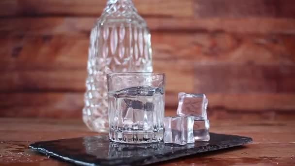 在玻璃杯中 人们在瓶子前 用冰块和伏特加或龙舌兰酒等清澈的白酒做着飞溅的画面 — 图库视频影像