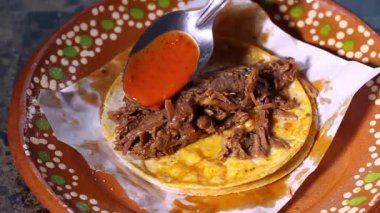 Birria de res taco 'ya acı sos koyan kişi yavaş hareket ediyor. Meksika yemeği