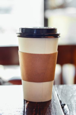 Kahve dükkanındaki tek kullanımlık kahve fincanının kapağı ahşap masada.