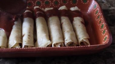 Tavuklu taco, enchiladas enmoladas üzerine siyah köstebek döken bir insan.