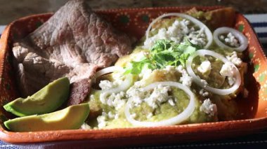 Yeşil soslu, peynirli, soğan halkalı, biftekli, avokado dilimli ve kişniş soslu lezzetli chilaquiles.