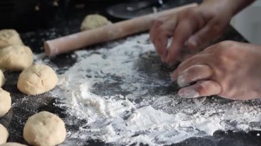 Fırıncı küçük ekmek ruloları hazırlıyor, un yüzeyinde hamur yoğuruyor.