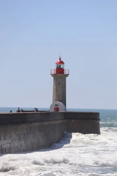 Deniz kıyısında deniz feneri, arka planda ada ve okyanus.