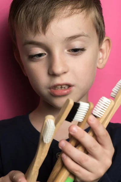 Dziecko Wyglądzie Europejskim Bada Wiele Bambusowych Szczoteczek Zębów Swoich Rękach — Zdjęcie stockowe
