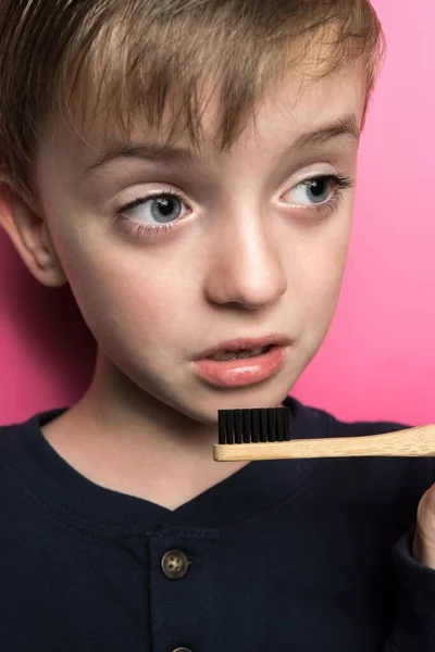 Dziecko Wyglądzie Europejskim Trzyma Rękach Bambusową Szczoteczkę Zębów Różowe Tło — Zdjęcie stockowe