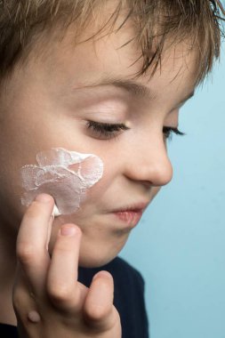 Avrupalı bir çocuk yanağına beyaz krem ya da merhem sürmüş. yakın plan fotoğraf.