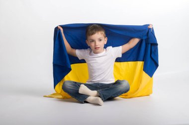 Beyaz bir arka planda Ukrayna bayrağı taşıyan Slav görünümlü küçük bir çocuk. yatay resim