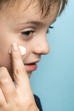 a little boy smears cream on his face. sun block. close-up