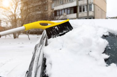 sweeping snow with a brush from a car on the street
