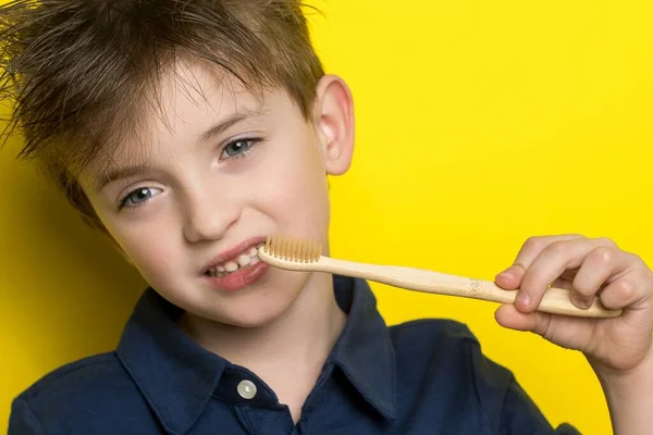 Mały Chłopiec Trzyma Rękach Szczoteczkę Zębów Bambusa Zdjęcie Poziome Żółtym — Zdjęcie stockowe