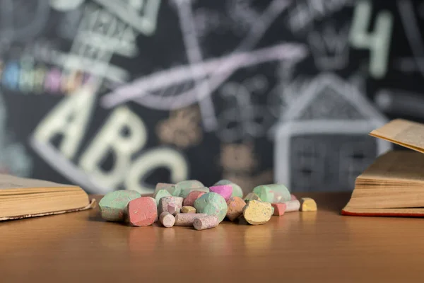 pieces of multi-colored chalk on a table against a slate wall background