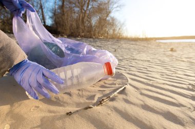 Nehir kıyısındaki çöp torbalarını temizliyorum. Gönüllüler bir dünya günü düzenler ve plastik şişe toplarlar.