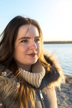 Gün batımında gölün kıyısındaki bir kızın yakın plan portresi.