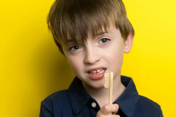 Mały Chłopiec Europejskim Wyglądzie Trzyma Dłoniach Bambusową Szczoteczkę Zębów Żółtym — Zdjęcie stockowe