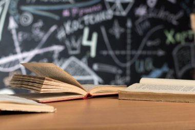 open books lie on a desk or table against a chalk-painted chalkboard wall clipart