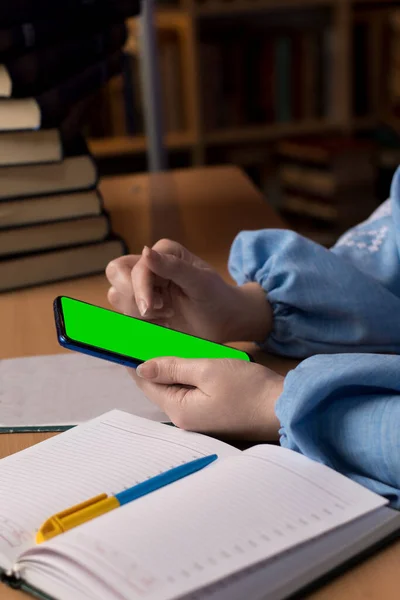 開いているノートパソコンの近くの女の子の手の中にあるスマートフォンです テキストのための場所を模倣 — ストック写真
