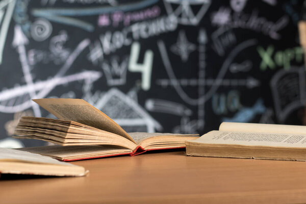 open books lie on a desk or table against a chalk-painted chalkboard wall