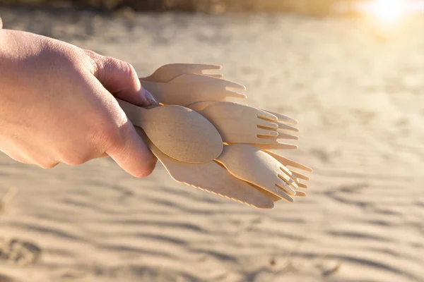 wooden spoons in hand on sand background