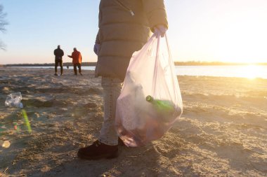 Gönüllü kız sahilde çöp topluyor. Dünya okyanusu kavramına plastik tehdidi
