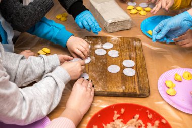 Birlikte ev yapımı mantı ya da ravioli yapan bir grup insan. Elleri hamuru şekillendiriyor ve tahta tahtaya doluyor. Geleneksel yemek hazırlama yoluyla aşçılık veya aile bağı kurma.