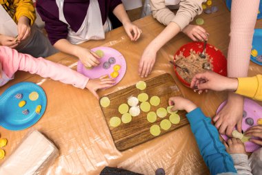 Birlikte ev yapımı mantı ya da ravioli yapan bir grup insan. Elleri hamuru şekillendiriyor ve tahta tahtaya doluyor. Geleneksel yemek hazırlama yoluyla aşçılık veya aile bağı kurma.