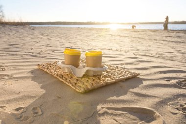 Pair of paper cups on a beach at sunset, ready for branding or design. Perfect for marketing materials, outdoor coffee themes, and customizable product placement in nature settings clipart