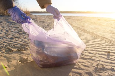 Close-up of hands in gloves collecting plastic waste from the beach. Environmental cleanup and sustainability concept. Perfect for topics on ocean pollution and eco-friendly lifestyle clipart