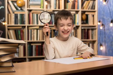 Young boy holding a magnifying glass, posing thoughtfully in a library with bookshelves in the background. Perfect for concepts of knowledge, learning, and child curiosity.  clipart