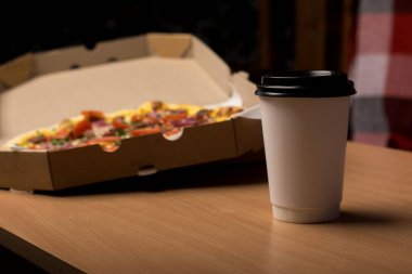 Domatesli pizza, kırmızı soğan ve tahta bir masada açık bir kutuda otlar. Paket yemek, pizza gecesi ve İtalyan mutfağı için ideal.