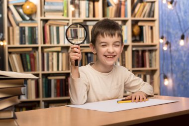 Masasında büyüteç, arka planında kitap rafları olan genç bir öğrenci. Merak ve eğitime odaklan. 