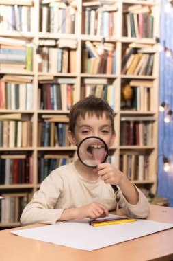 Neşeli çocuk ağzının önünde büyüteç tutuyor, dilini büyütüyor ve gülümsüyor. Çocukluk merakı, keşif ve eğlenceli öğrenme anları için mükemmel bir kavram.